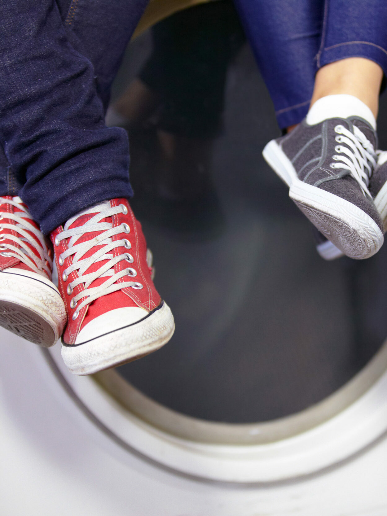 Due persone sono sedute con le sneaker sopra le lavatrici