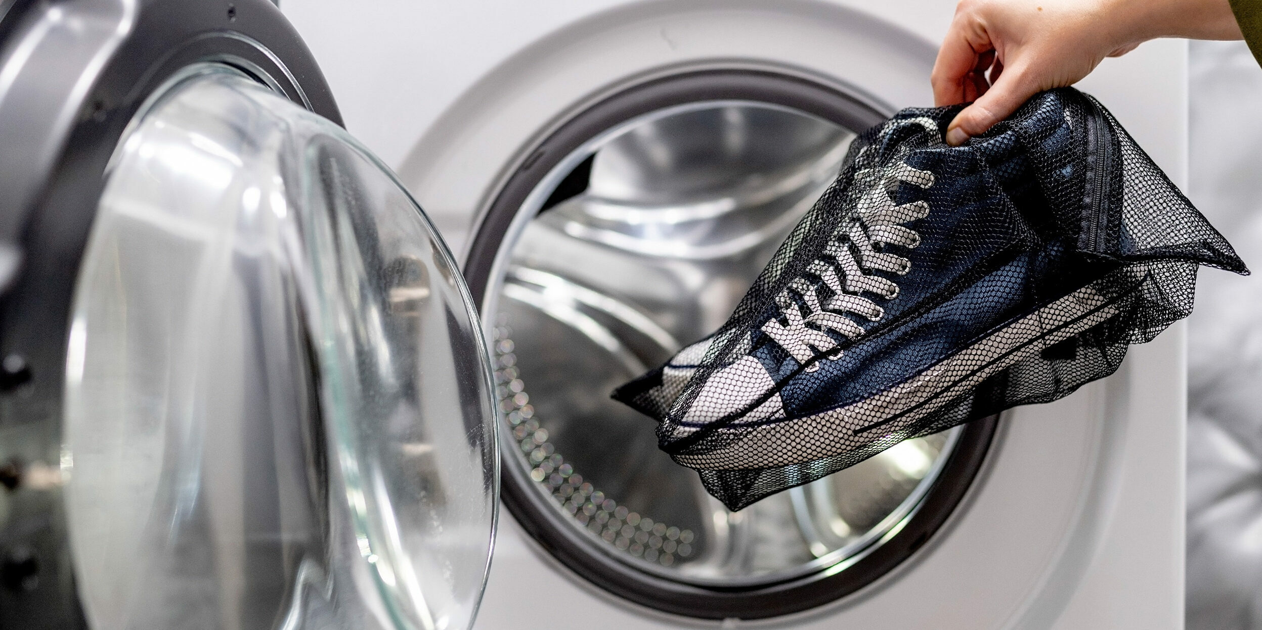 Sneakers bianche in un sacco per il bucato pronte per la lavatrice.