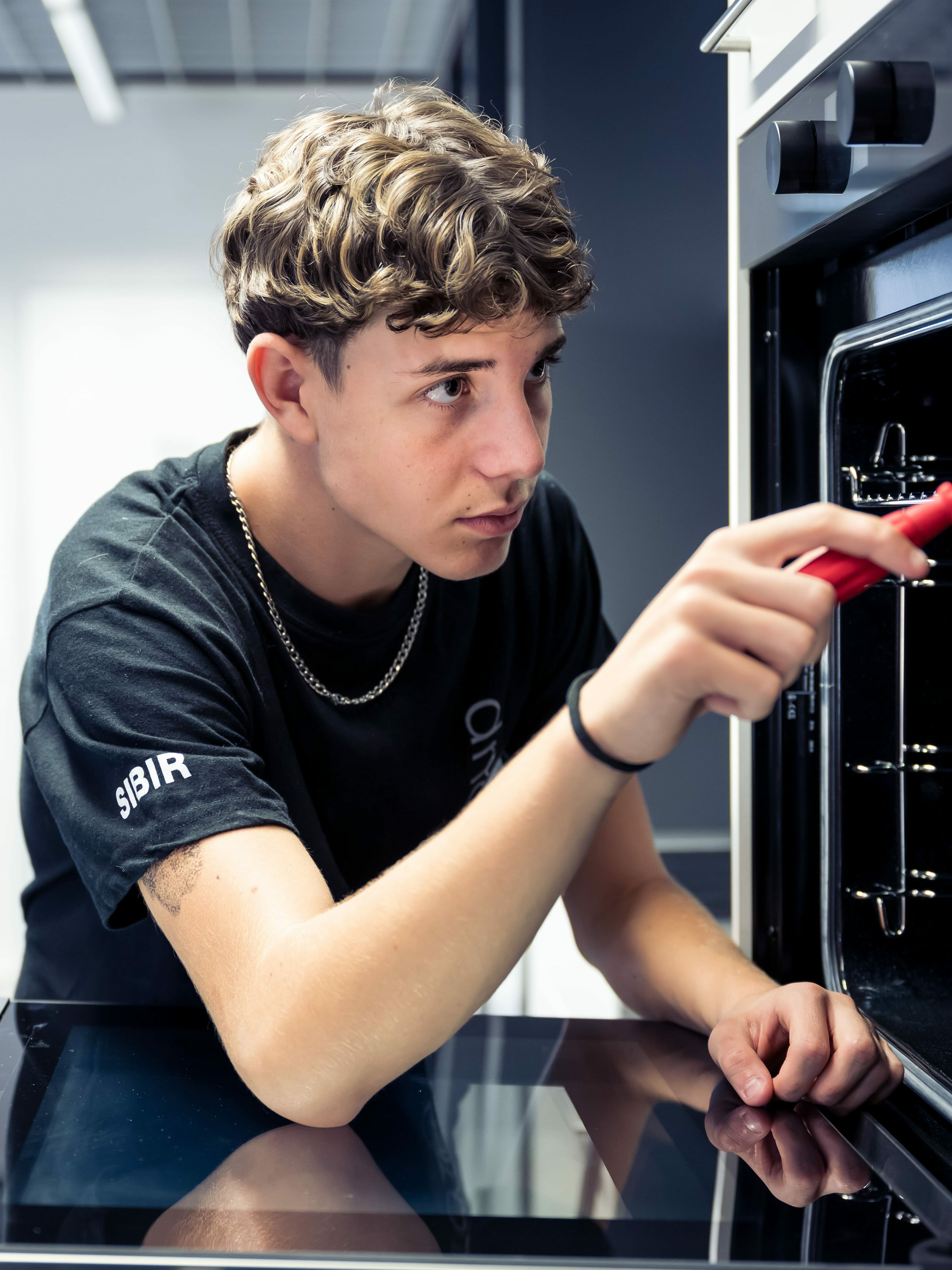 Bild Lehrling am Backofen Schrauben